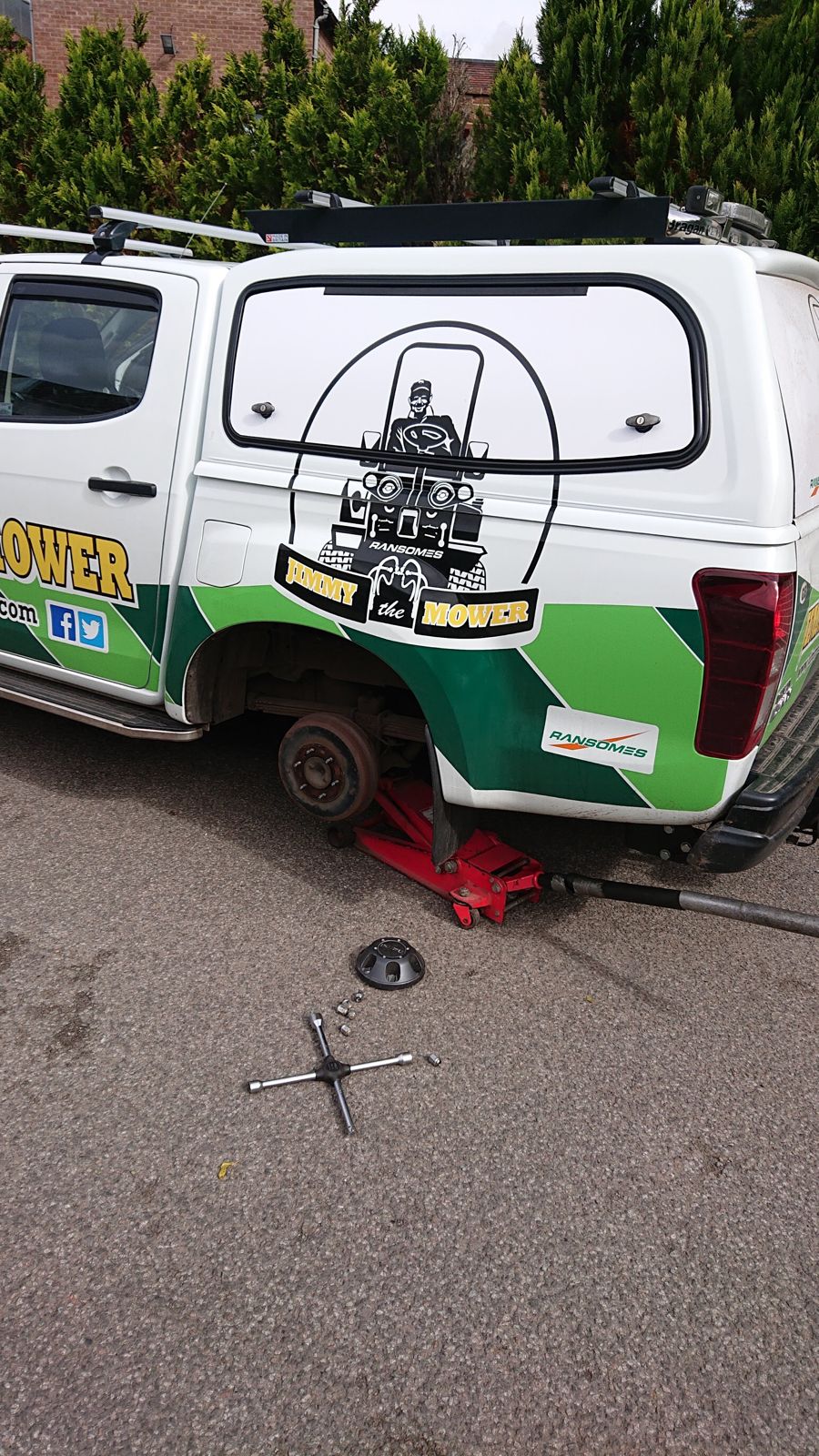 A pickup raised on a jack in the yard with its rear wheel removed